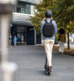 A woman on an e-scooter on a pavement.