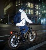 A male cycling at night whilst wearing a highly reflective jacket.